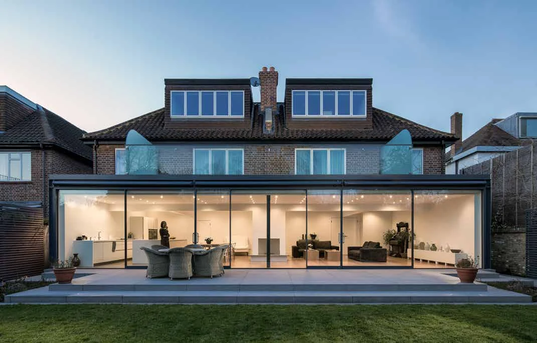 Frameless sliding doors across a house extension opening onto a garden patio